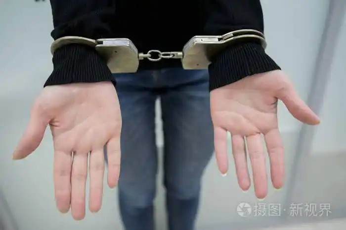 照片 特写镜头.被逮捕的人用手铐将双手铐在灰色背景上背部.