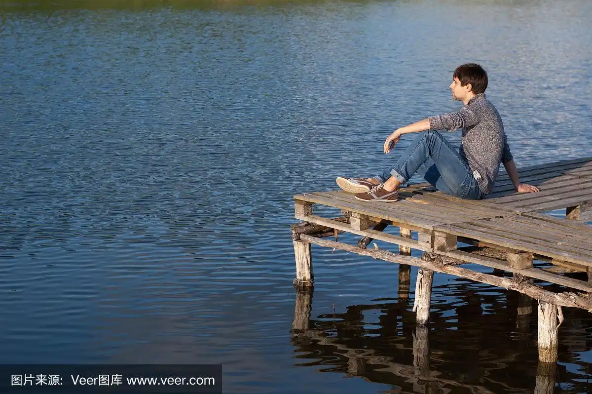 一个人坐在湖边的码头上