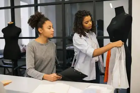 设计师成功年轻有吸引力的设计师和熟练的服装制造商或裁缝一起工作在