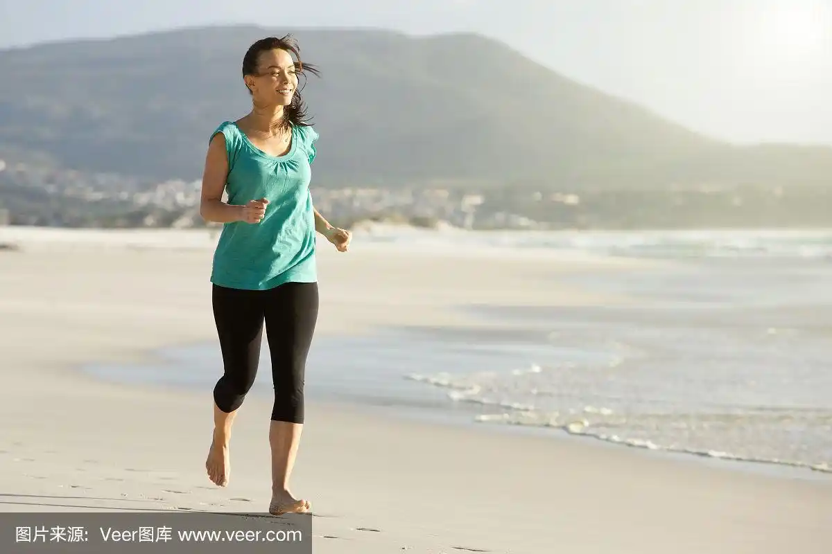 快乐的年轻女子赤脚在海滩上跑步