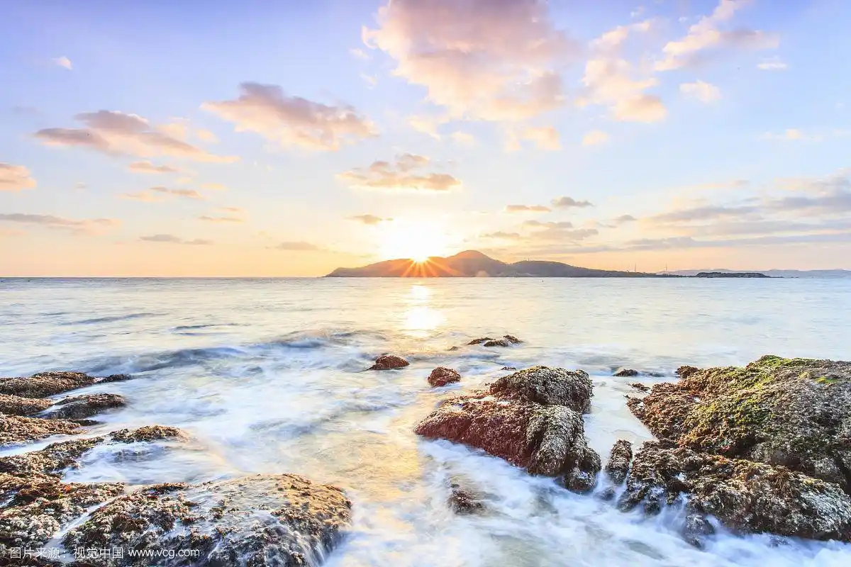 蓝天白云下的日出海面和礁石