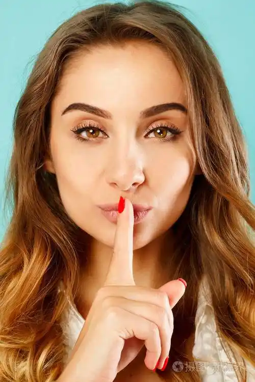 年轻漂亮的女性说嘘的手势在蓝色的背景