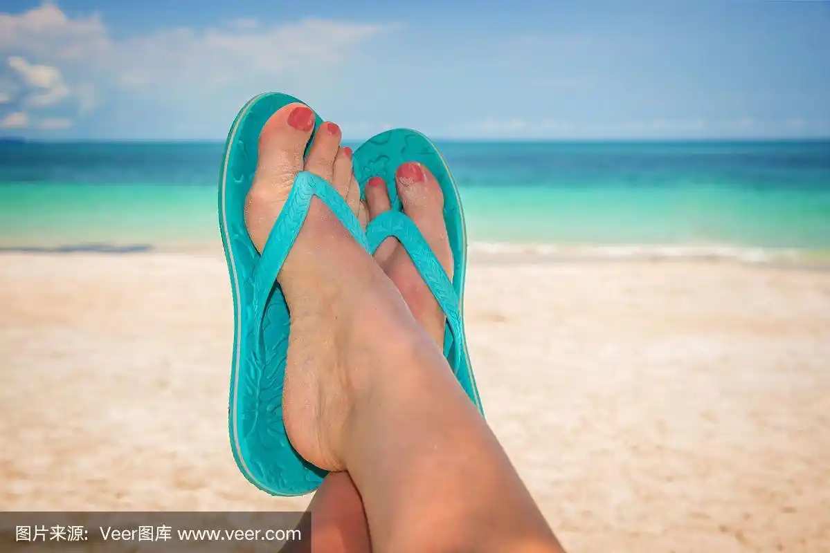 穿着蓝色人字拖的女人脚,沙滩和大海