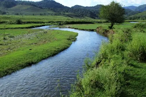 清澈的小河曲曲弯弯从中间穿过,静静的水面映衬着蓝天白云,坝下稍有踹