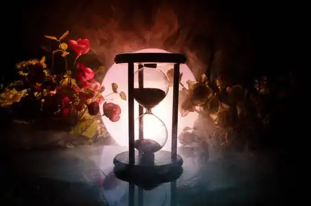 在深色背景上的烟气中的沙漏轮廓.与花照片