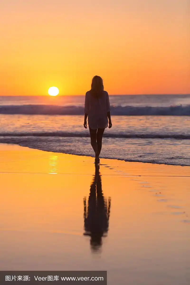 在夕阳下的沙滩上漫步的女士.