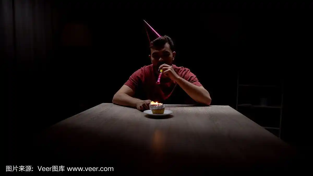 孤独的男人们看着蛋糕上燃烧的蜡烛庆祝生日