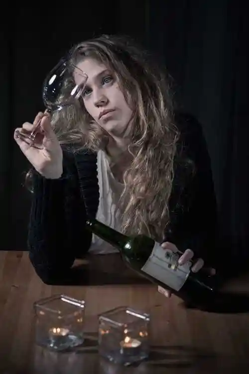 喝酒的年轻女人图片-坐在桌子旁边倒酒的女人素材-高清图片-摄影照片