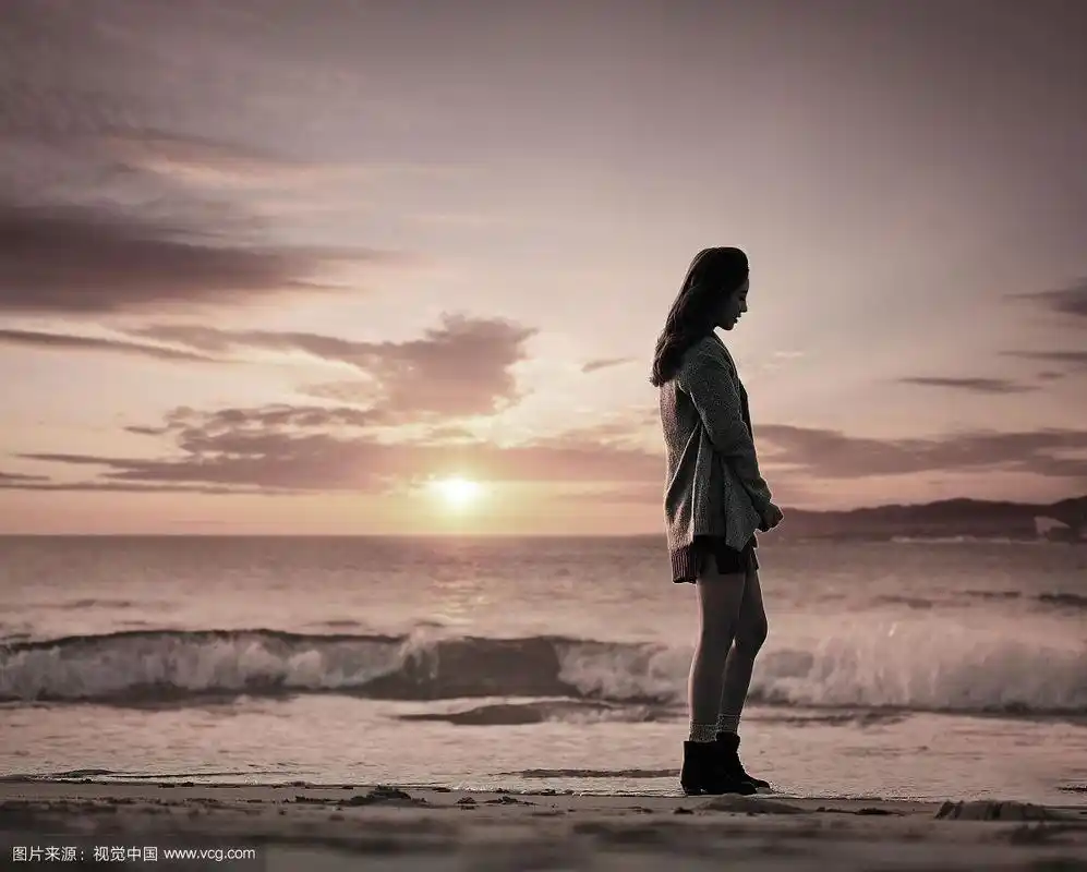 日落时分,女人站在沙滩上的摄影