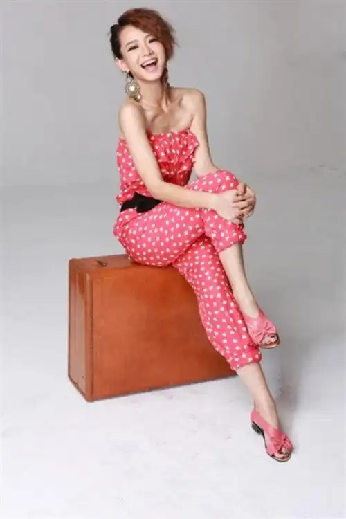 戚薇内搭一件红色的衬衫,穿着一件横格纹的长裙,脚上穿着一双黑色的