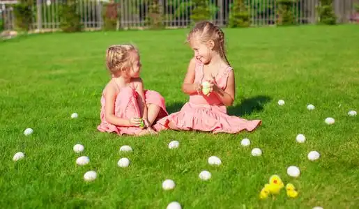 在绿色的复活节彩蛋两个可爱的小女孩,在绿色草地上玩复活节彩蛋照片