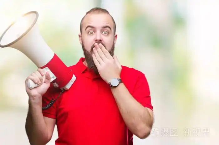 年轻的白种人通过扩音器在孤立的背景上大声喊叫捂住嘴