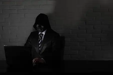 戴着黑色面具和头巾的黑客在桌旁照片
