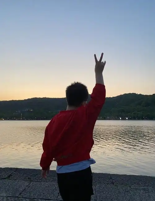 " 照片中,安吉和小鱼儿身穿着同款的红色卫衣,站在夕阳下比耶,两兄弟