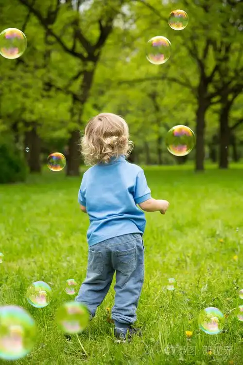 可爱的卷发婴儿带肥皂泡. 孩子们在玩跑步