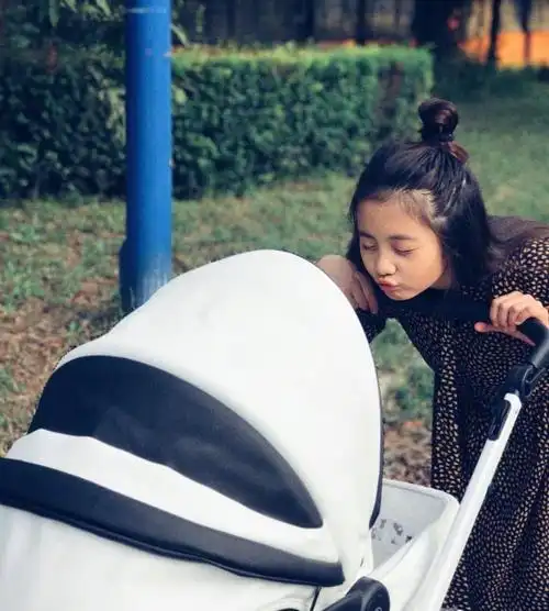 小家伙躺在婴儿椅中,胖乎乎的小手十分可爱,多妹闻着弟弟的小脚丫