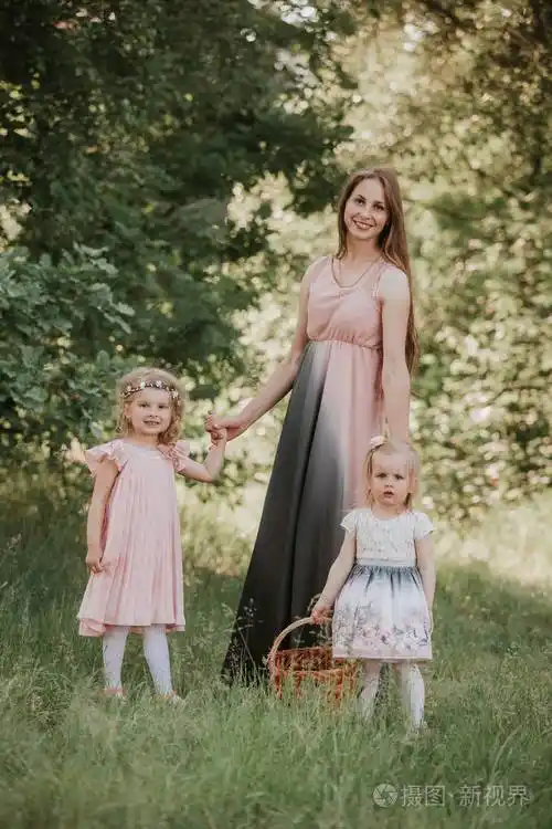 公园里有两个女儿的妈妈的画像母亲和两个女儿在旋转母亲牵着女儿们的