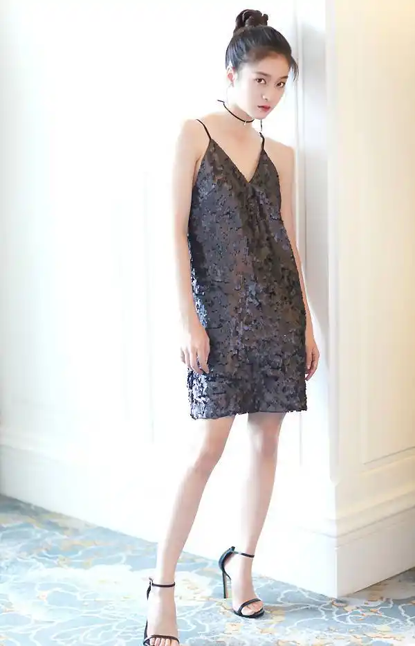 张雪迎身着黑色亮片吊带短裙,搭配黑色一字带高跟鞋,高高梳起的麻花辫