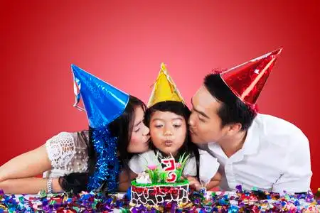 一家四口生日当父母亲吻他们的孩子在生日聚会上照片