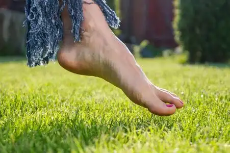 赤脚走在绿色的草地上的女人照片