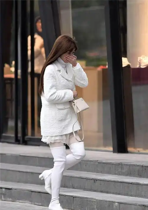 白色粗跟过膝靴搭配白色丝袜毛衣和外套都是白色的