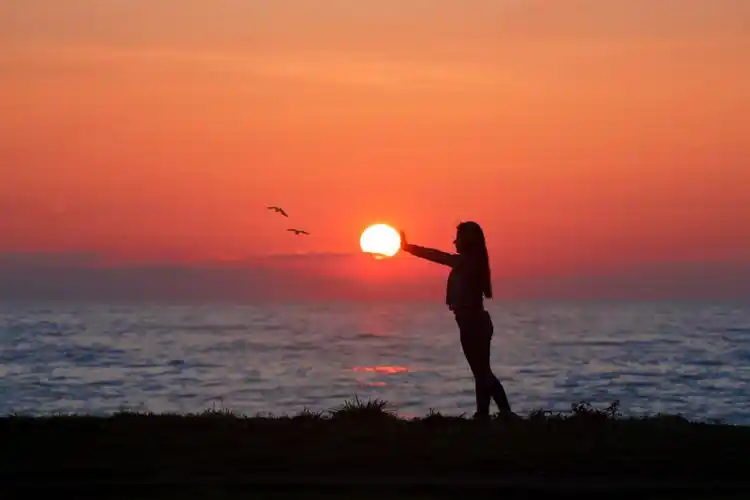 黎明时分一名女子站在海边的照片|云,人,傍晚,坐,天空,太阳,头发,女人