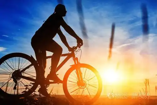 在美丽的夕阳的天空背景上的自行车骑车人的侧面影像