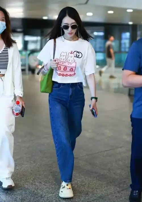 冷白皮的李小冉机场造型很清新,白色卡通t恤衫搭配蓝色牛仔裤,时髦
