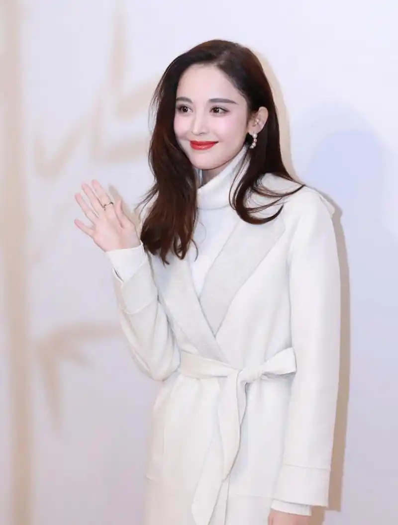 看古力娜扎长发披肩,穿着白色高领羊毛衫,撘配白色腰带裙,肤白貌美,洁