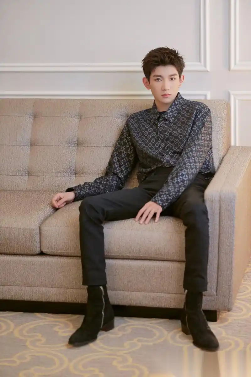 照片中王源随性坐在沙发一角直视镜头,眼神杀霸气十足