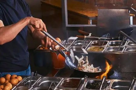 炒菜锅炒菜炒菜炒饭在灰混凝土背景下炒菜锅炒面虾厨师炒菜锅炒菜炒菜