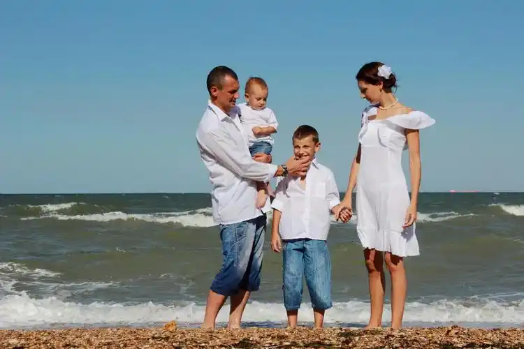 游玩的一家四口穿着泳装戴着太阳镜的两位小朋友在海边玩耍幸福童年