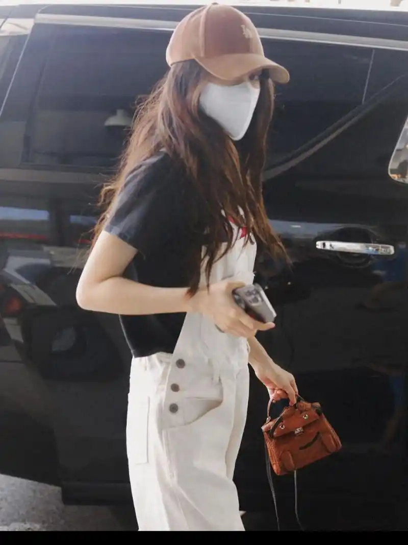 杨颖现身机场的私服穿搭 身穿复古卡通印花短袖t恤, 外搭白色背带牛仔