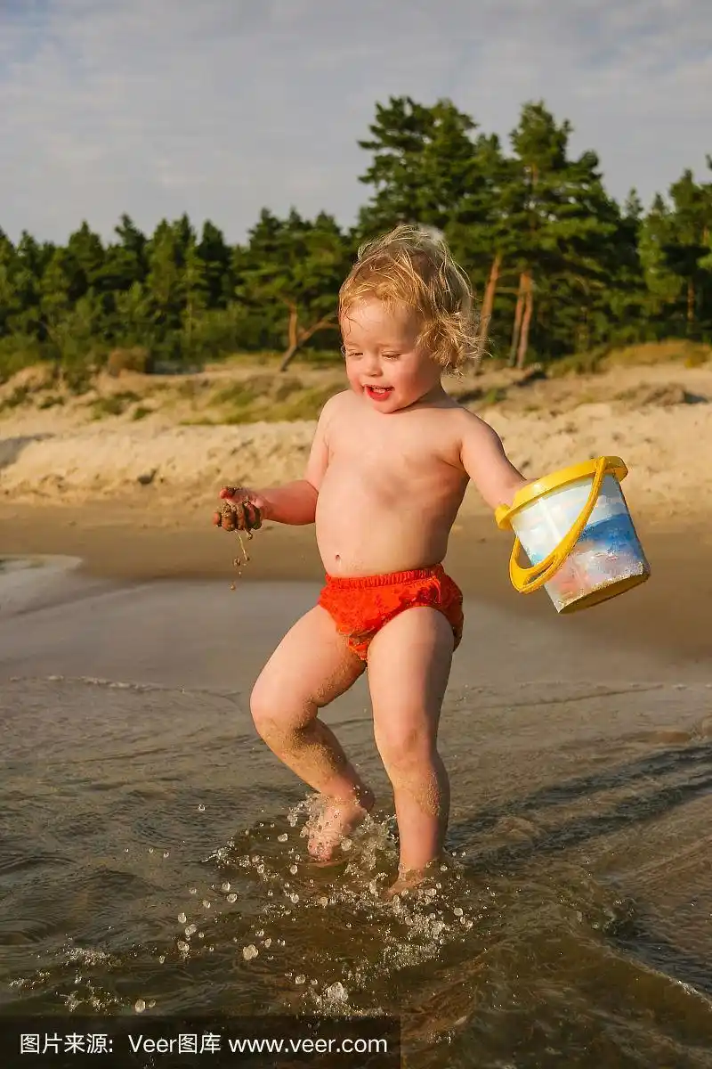 小女孩拿着水桶在海边