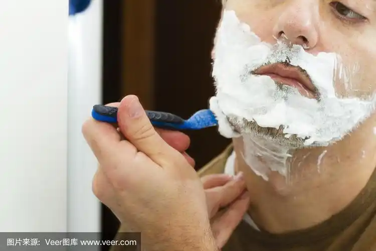 一个成年男子用剃刀刮胡子的特写