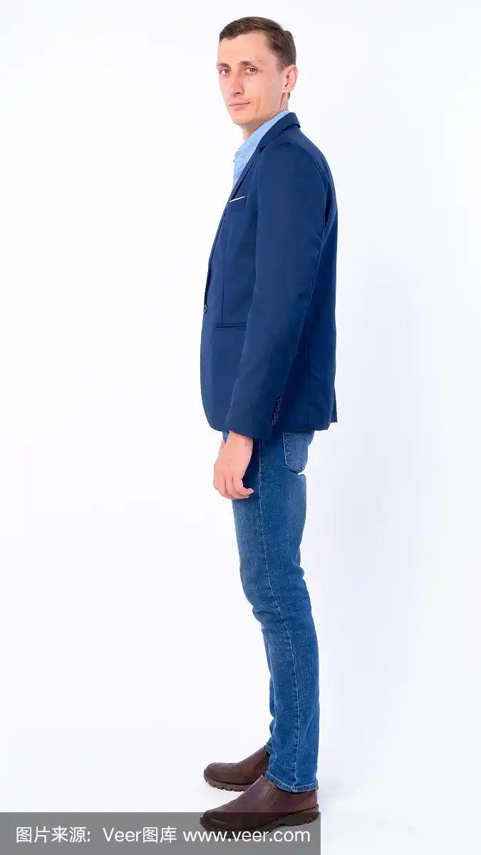 全身拍摄的侧面视图的商人在西装看着相机