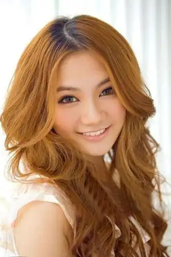 质感丰盈的女生长卷发烫发发型,棕黄色的染发亮眼十足,蓬松质感的