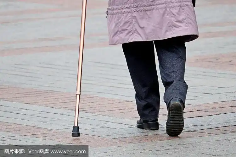 拄着拐杖沿街行走的一瘸一拐的妇女