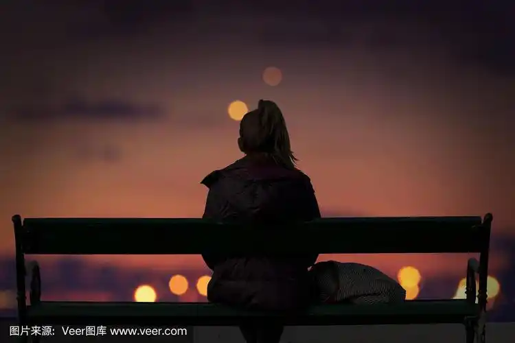 一个女孩的剪影看着城市的灯光散焦