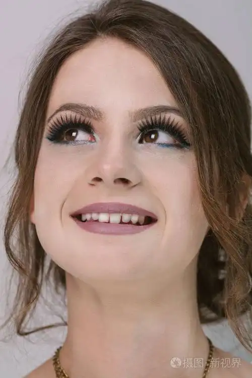 特写美丽快乐的年轻女子的肖像,微笑着,看着灰色的东西