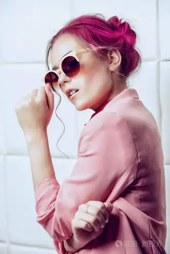 漂亮的粉红色头发的女孩在明亮的夏天的衣服和太阳镜摆在光的背景.