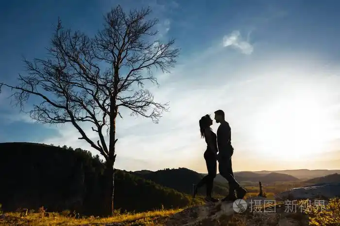 一对相爱的夫妇的剪影日落时拥抱的男人和女孩情侣旅行大自然中的情人
