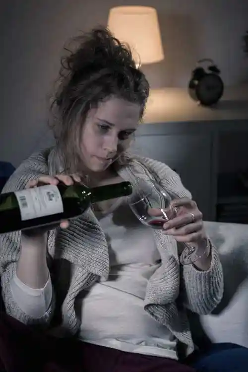 坐在桌子旁边倒酒的女人