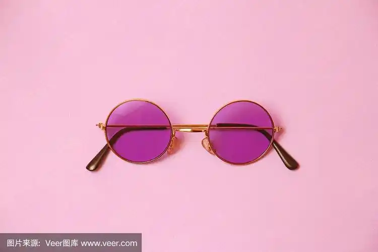 单一透明圆形粉红色眼镜在均匀的珊瑚背景上,太阳臂眼镜是关闭的,正面