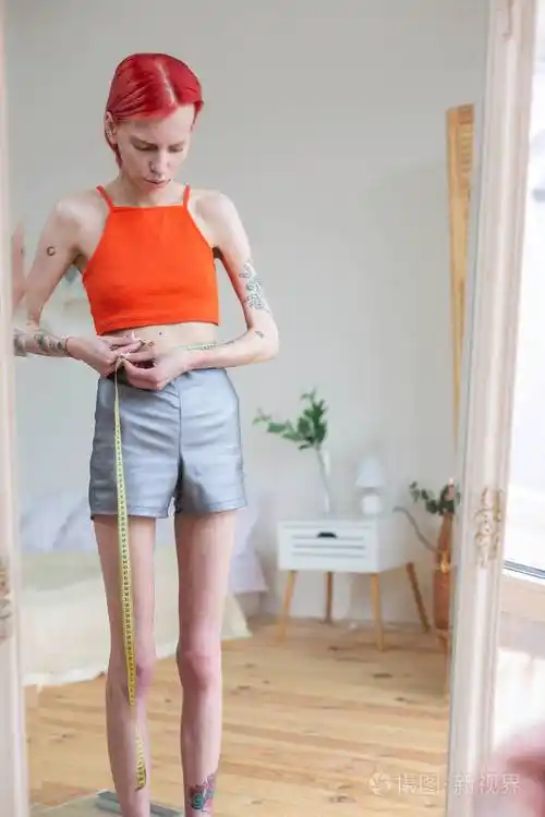 瘦骨嶙峋的女人用卷尺量腰围