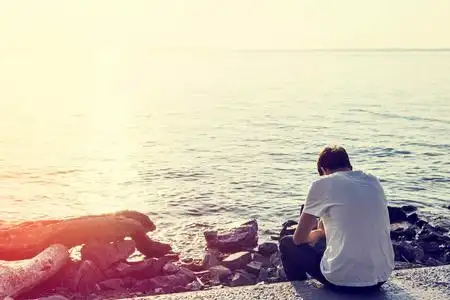 孤独的亚洲男生在海边的悬崖上看日出的高处的孤独女孩海边孤独的女孩