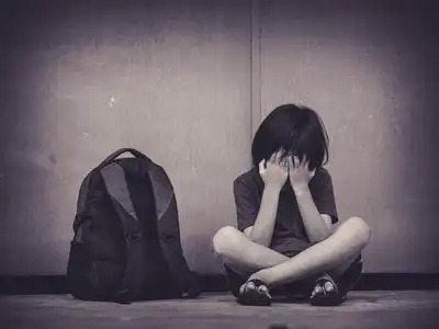 伤心的孩子坐在地板上等待父的书包照片