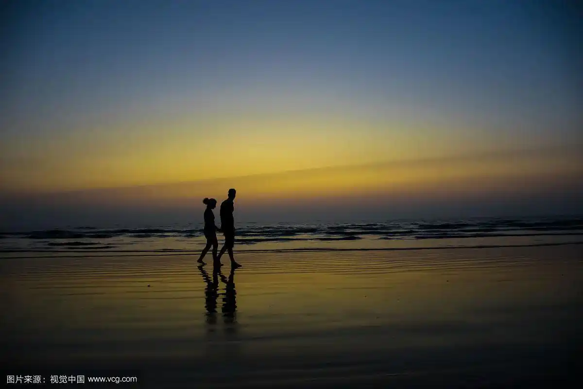 黄昏时分,一对夫妇在印度海滩上散步的剪影