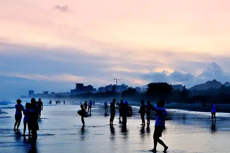 三亚海边傍晚人们悠闲在海滩上散步