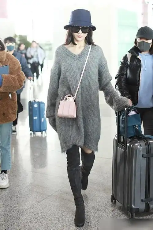王鸥身穿一件灰色长款毛衣,斜挎一个粉色的小包包,脚踩黑色高筒靴